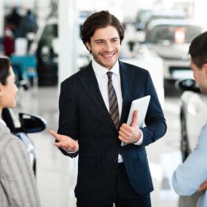 Man talks to customers at a car dealership