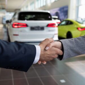 People shaking hands at a car dealership.