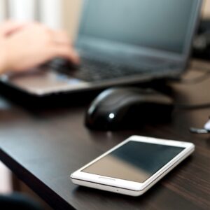 Person typing on a computer with their phone next to them